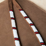 Close up of the white, red and black hand beaded zipper pull ties of the small sand brown suede leather pouch bag