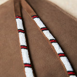 Close up of the white, red and black hand beaded zipper pull ties of the small sand brown suede leather pouch bag