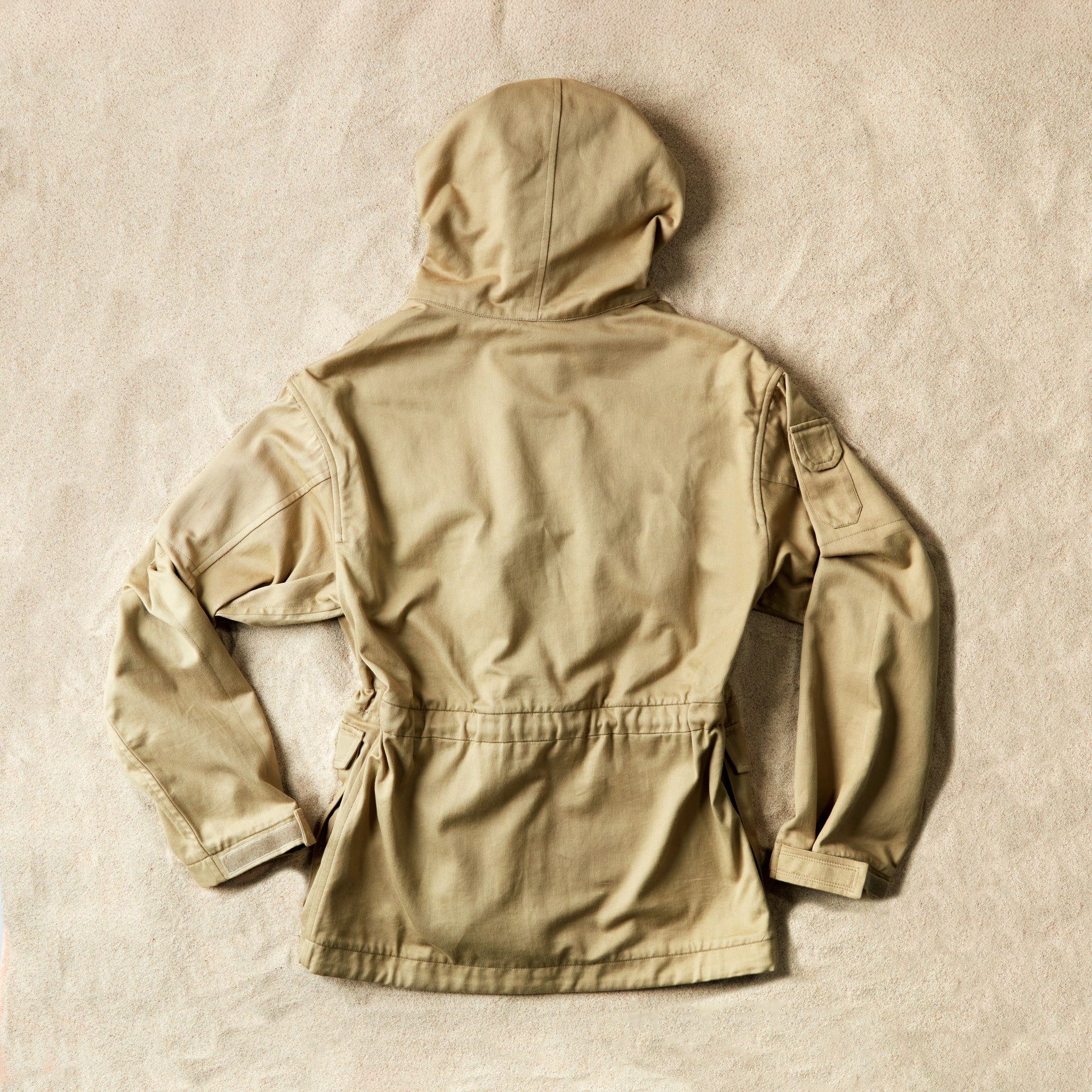 Back view of the khaki ranger safari hooded jacket against sand background