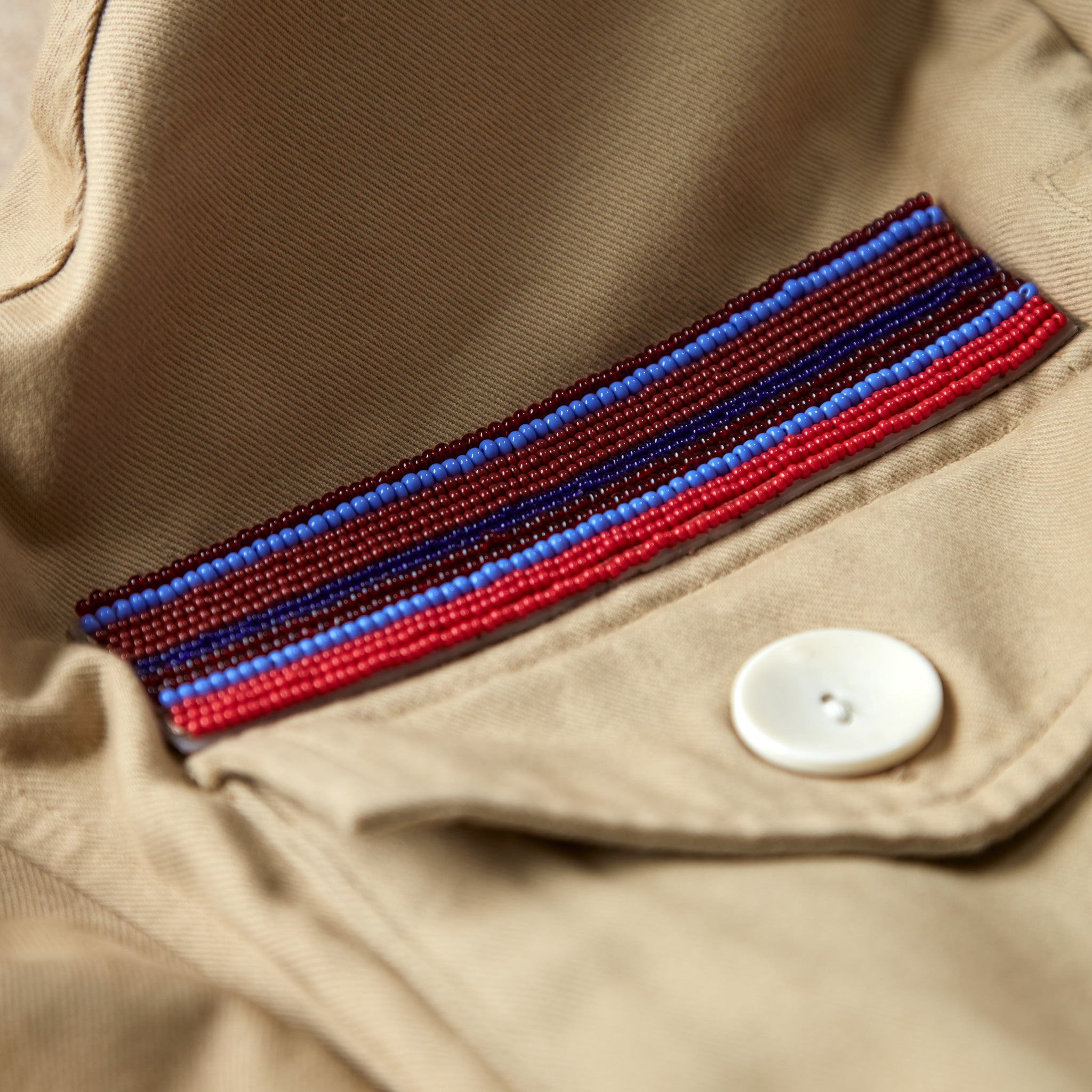 Close up view of colorful hand beaded patch above one of the pockets of the khaki ranger safari jacket