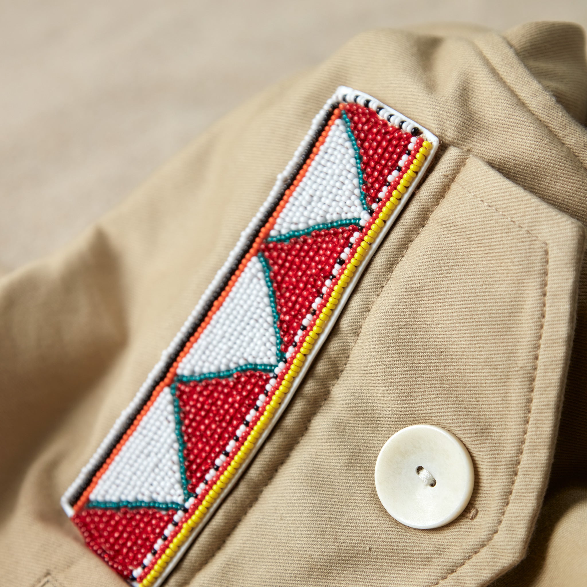 Close up view of colorful geometric hand beaded patch on the khaki ranger safari jacket