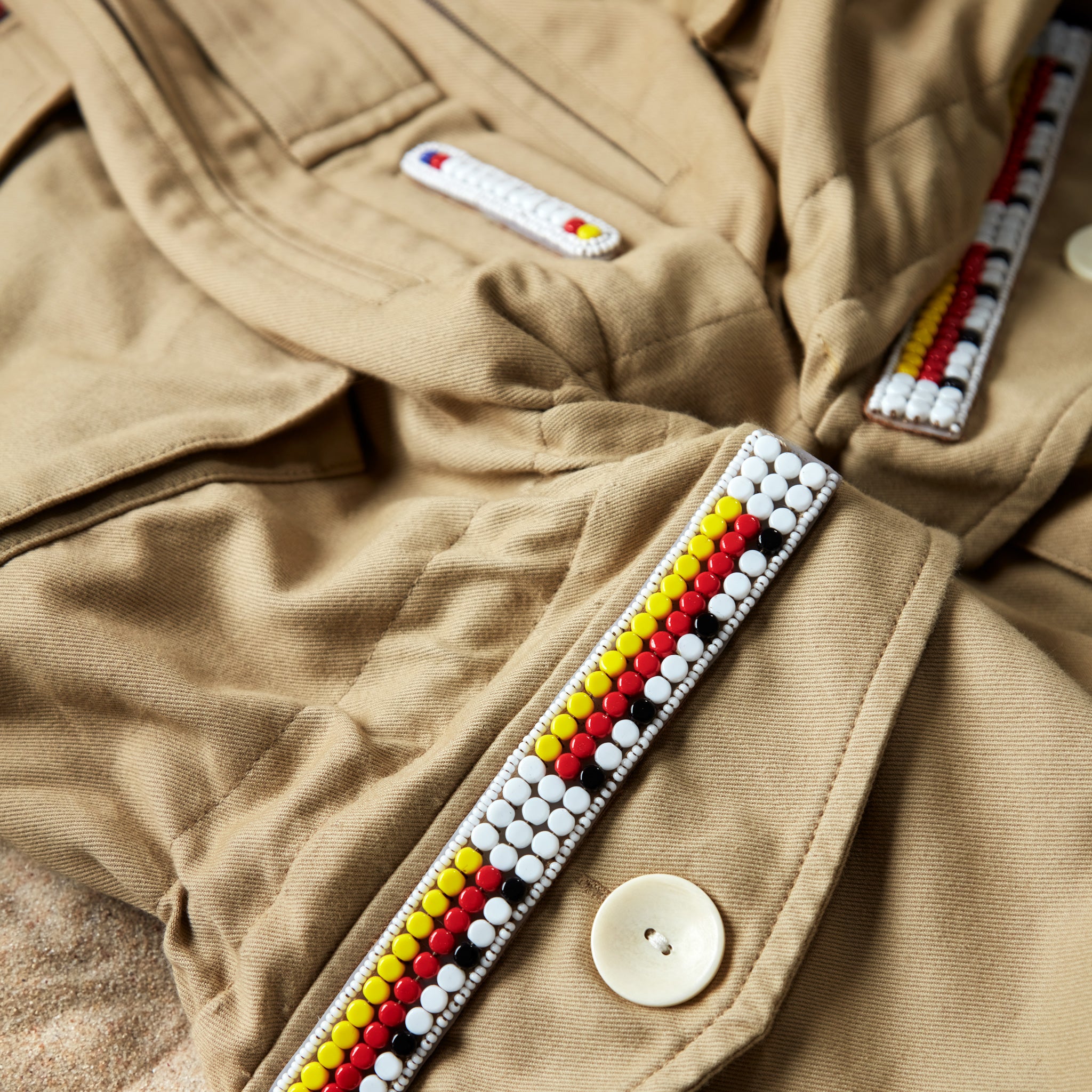 Detail view of colorful hand beaded patches on the khaki ranger safari jacket