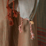 A close up of the twisted fringe of the brown and grey sarong/pareo featuring a small elephant charm.