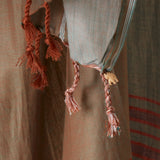 A close up of the twisted fringe of the brown and grey sarong/pareo featuring a small elephant charm.