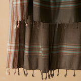 Close up detail of braided fringe of a dark gray cotton pareo/sarong
with striped borders in beige, brown, and light blue.