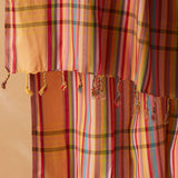 A close up view of a multicolored striped pareo/sarong with fringed tassels