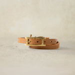 Back View of brown leather bracelet with brass elephant and brass buckle closure on a sand background