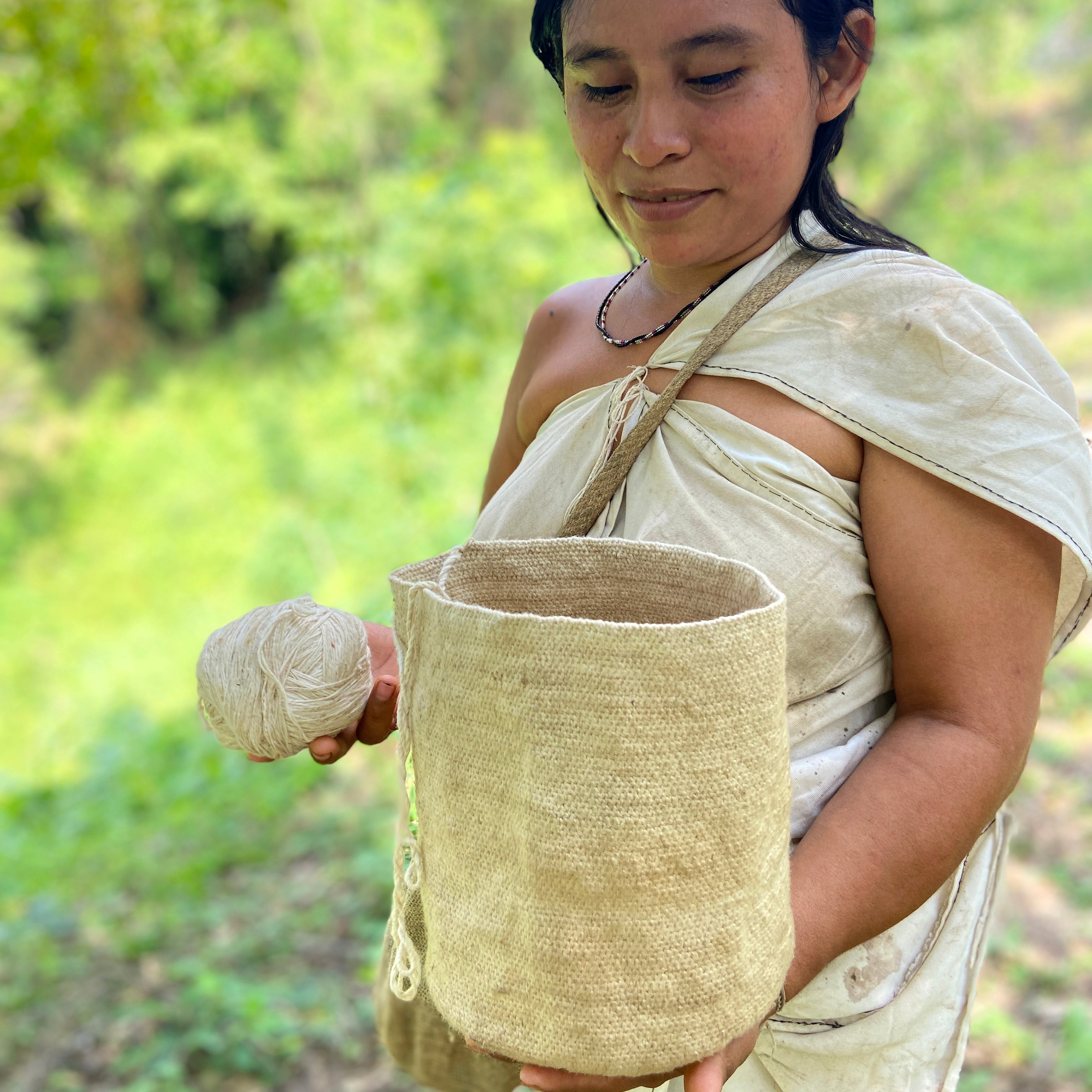 Woman holding a woven basket and ball of yarn outdoors