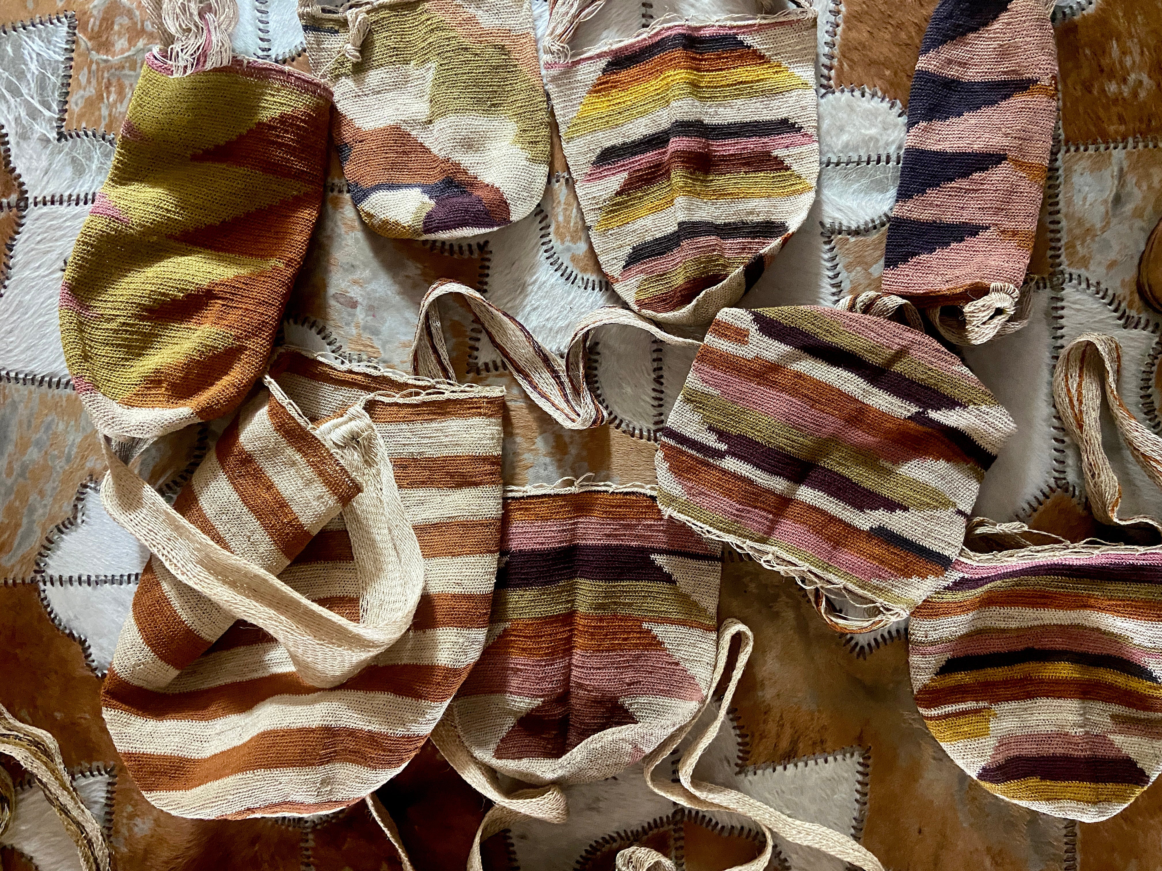 Collection of mochila bags in earthy tones on a patched background