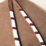 Close up of the white, red and black hand beaded zipper pull ties of the small sand brown suede leather pouch bag