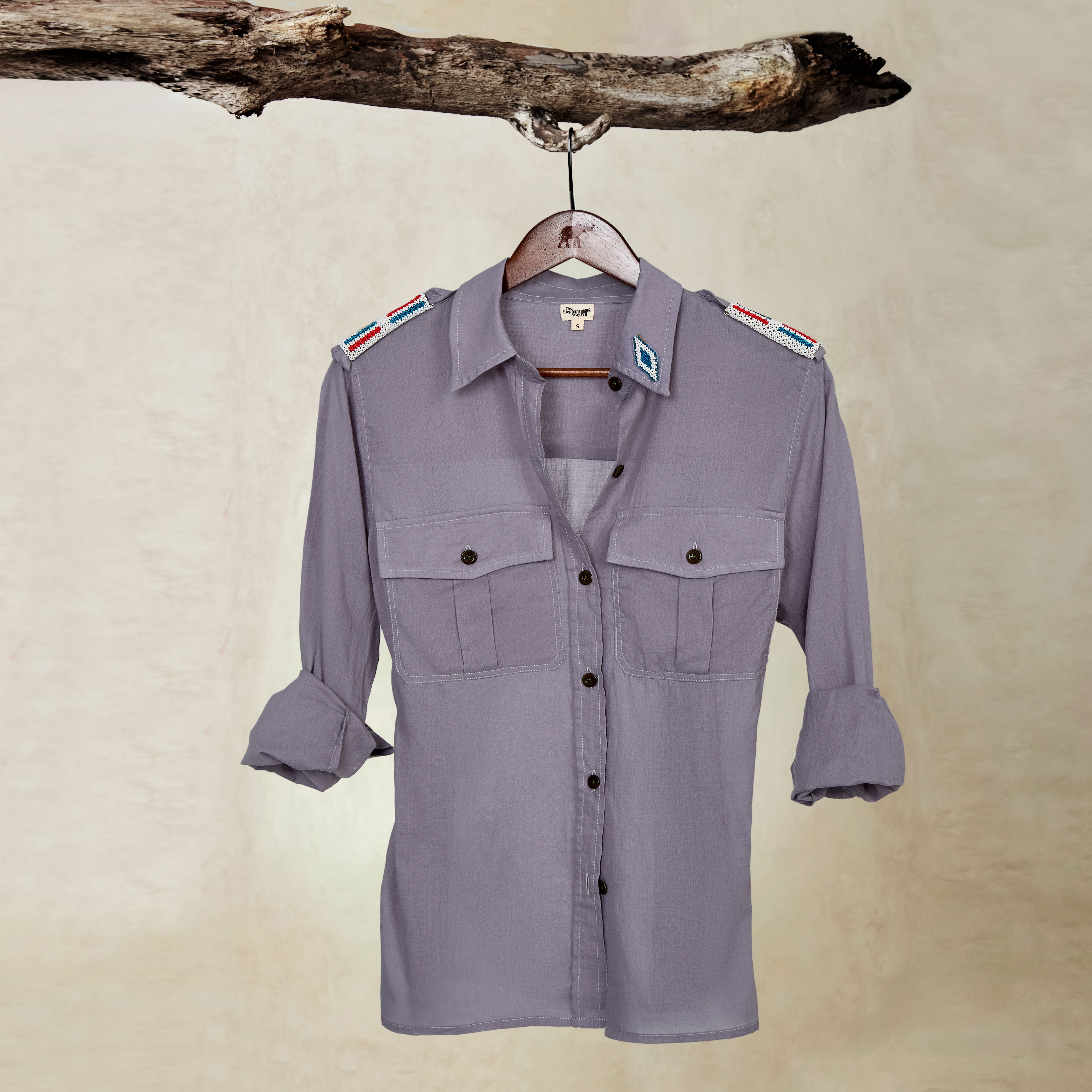 Grey Lightweight Ranger Shirt with White and Colorful Beaded Epaulettes on a hanger from a branch