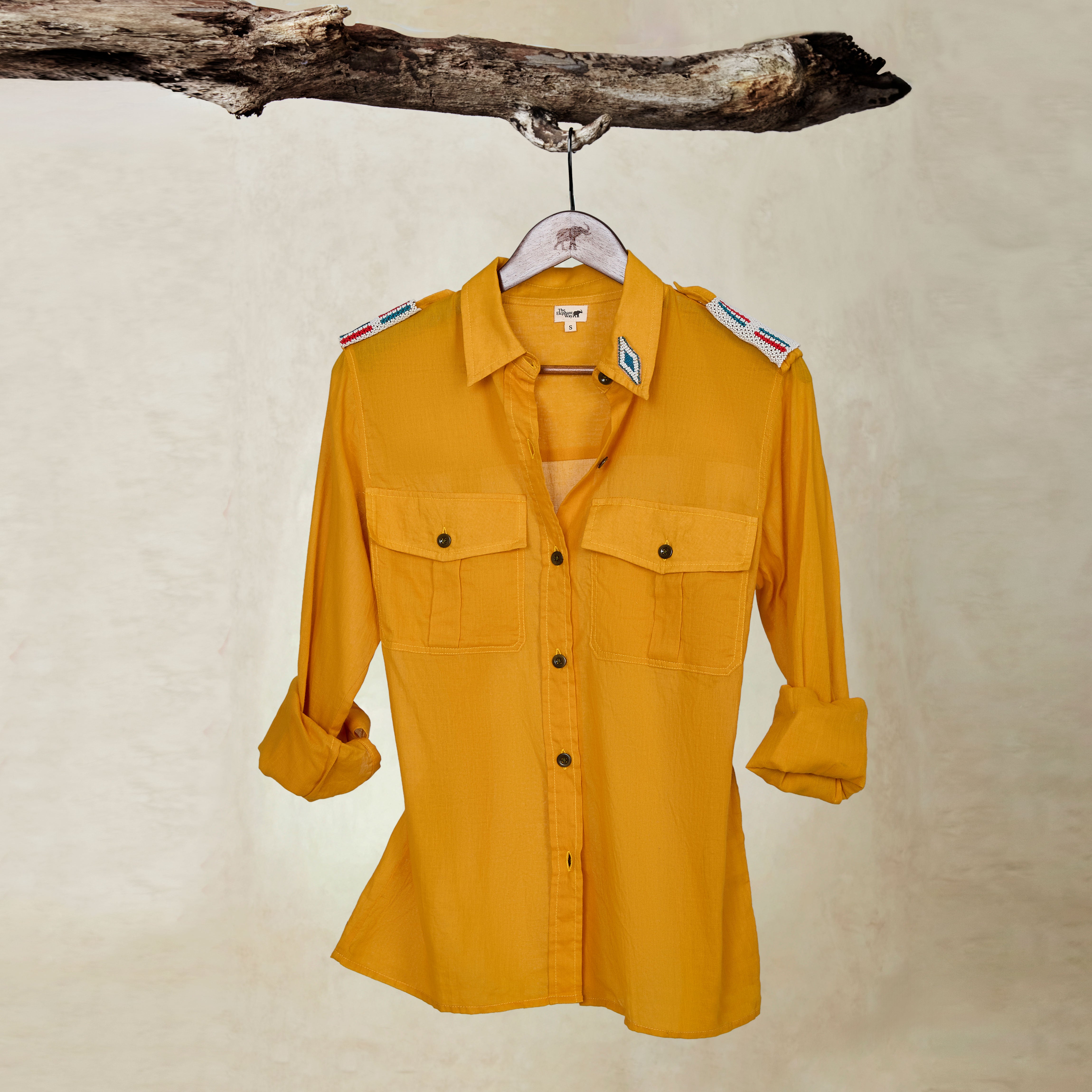 Golden Yellow  Lightweight Ranger Shirt with White and Colorful Beaded Epaulettes on a hanger from a branch