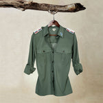Khaki Green Lightweight Ranger Shirt with White and Colorful Beaded Epaulettes on a hanger from a branch