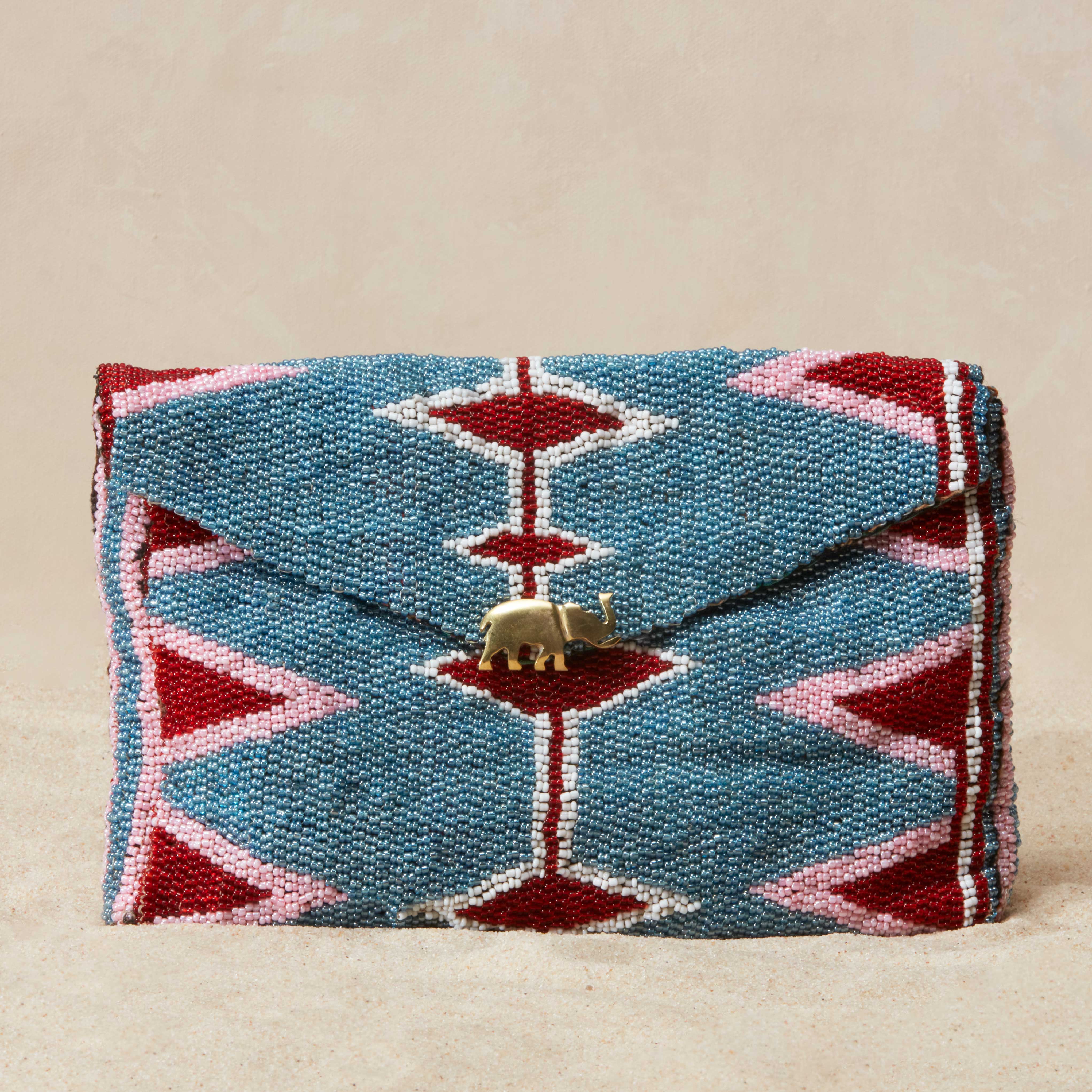 Beaded pouch with geometric pattern and brass elephant on a beige background