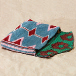 Beaded clutch in a colorful geometric pattern lined with colorful kanga fabric on a sand background