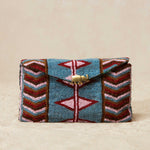 Colorful beaded clutch bag with geometric patterns and a brass elephant on a beige background