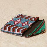 Multicolored patterned beaded pouch and colorful kanga fabric lining on a beige surface