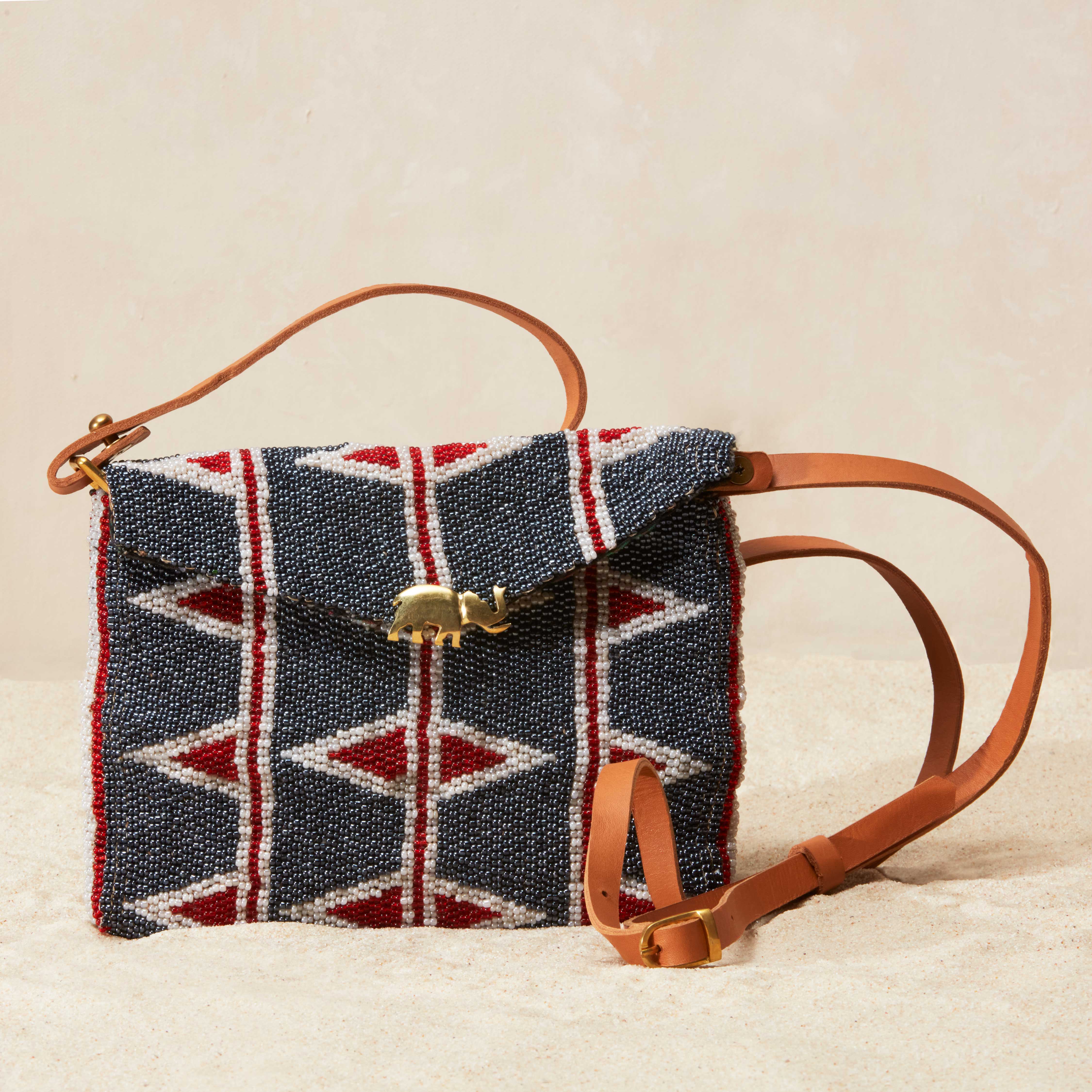 Beaded handbag with geometric pattern and leather strap on a beige background