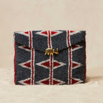 Beaded clutch with geometric pattern and brass elephant on a beige background