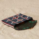 Beaded clutch with brown kanga fabric lining on a sand background