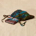 Colorful beaded clutch inside  colorful kanga fabric dust bag on a sandy surface