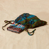 Colorful beaded clutch inside  colorful kanga fabric dust bag on a sandy surface