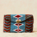 Beaded clutch bag with geometric pattern and brass elephant on a beige background