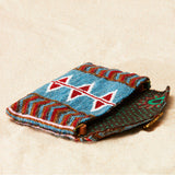Colorful beaded pouch with geometric patterns and brown kanga fabric lining on a beige background