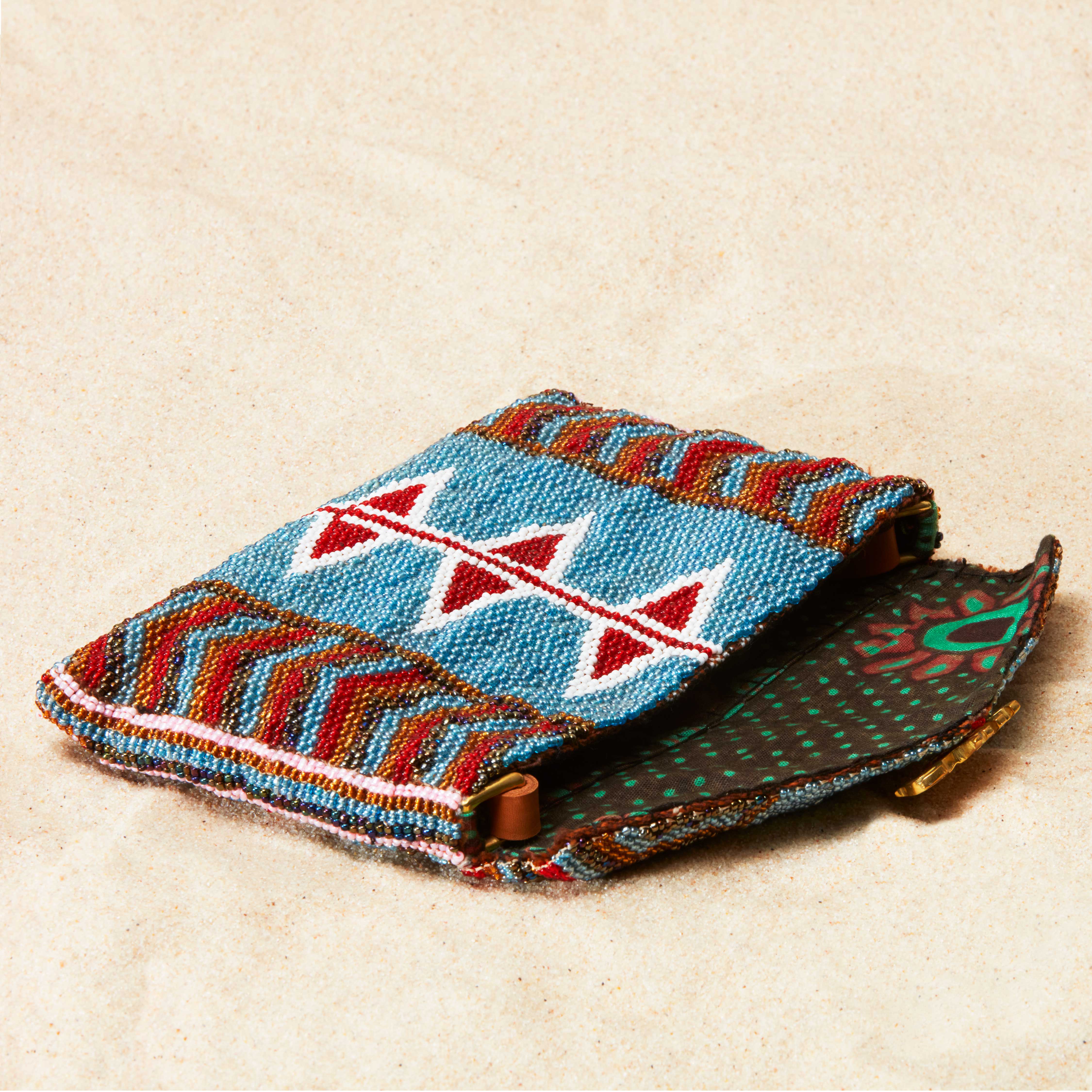 Colorful beaded pouch with geometric patterns and brown kanga fabric lining on a beige background