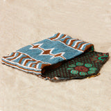Beaded geometric clutch with brown kanga fabric lining on a sand background