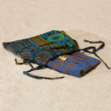 Brown and purple beaded clutch with brass elephant in a pattern kanga fabric dust bag on a sandy surface