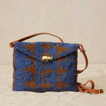 Blue and brown beaded handbag with a brass elephant and brown leather strap on a beige background