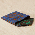 Beaded blue and brown patterned pouch with a green and brown kanga fabric lining on a beige surface