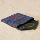 Beaded blue and brown patterned pouch with a green and brown kanga fabric lining on a beige surface