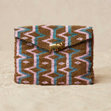 Beaded clutch with geometric pattern  and a brass elephant on a beige background