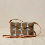 Beaded handbag with geometric pattern and leather strap on a beige background
