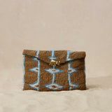 Gold, white and blue beaded pouch with geometric pattern  and brass elephant on a beige background