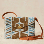 Beaded handbag with geometric pattern and brown handle on beige background