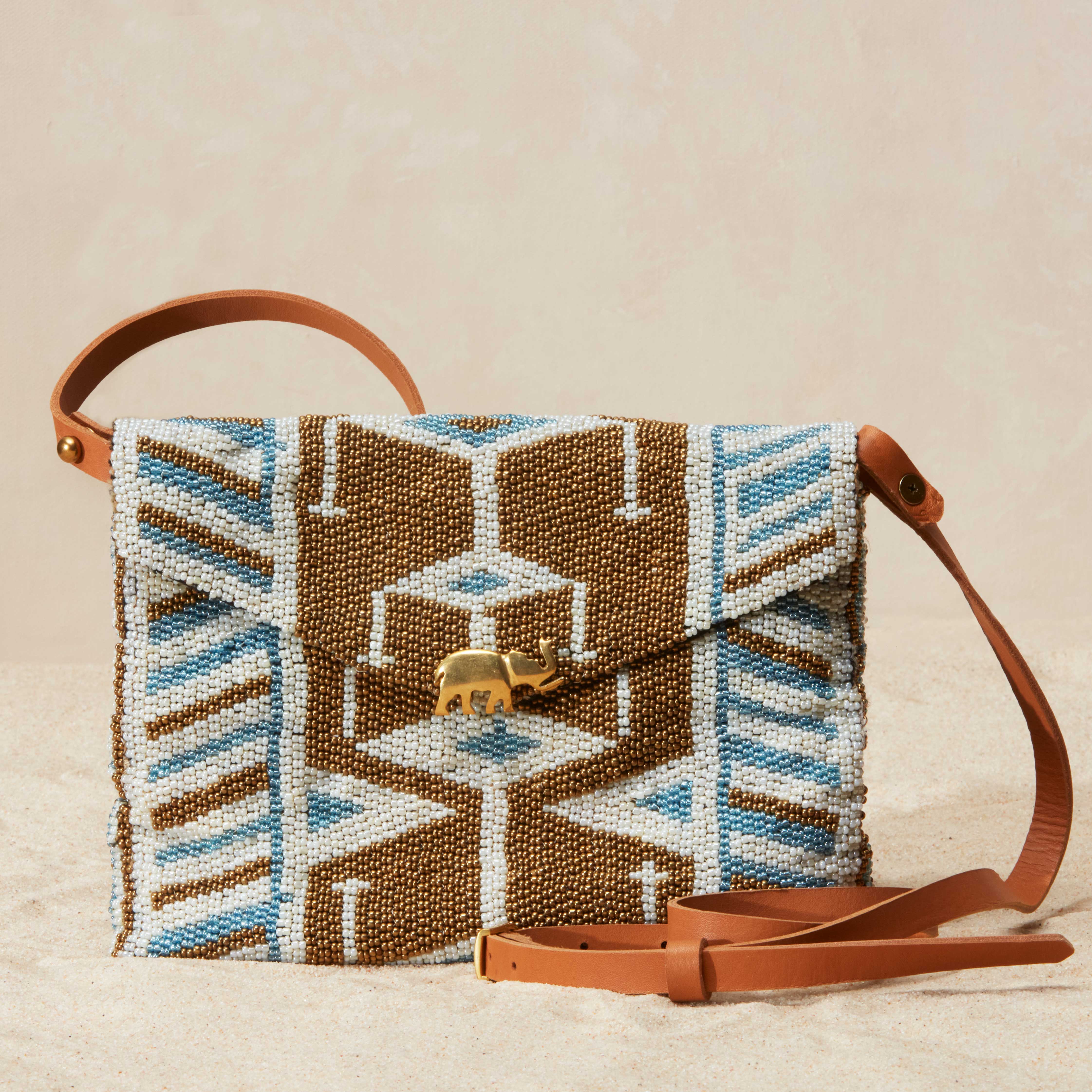 Beaded handbag with geometric pattern and brown handle on beige background