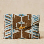 Beaded clutch with geometric pattern and brass elephant  on a beige background