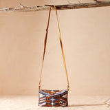 Small crossbody beaded handbag with a patterned design hanging on a branch