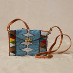 Colorful beaded handbag with geometric pattern and brown leather strap on a beige background