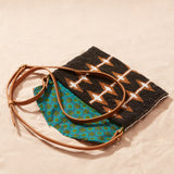 Beaded geometrically patterned handbag with a leather strap open showing the colorful kanga fabric lining