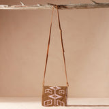 Pink and gold beaded handbag with a leather strap hanging on a branch