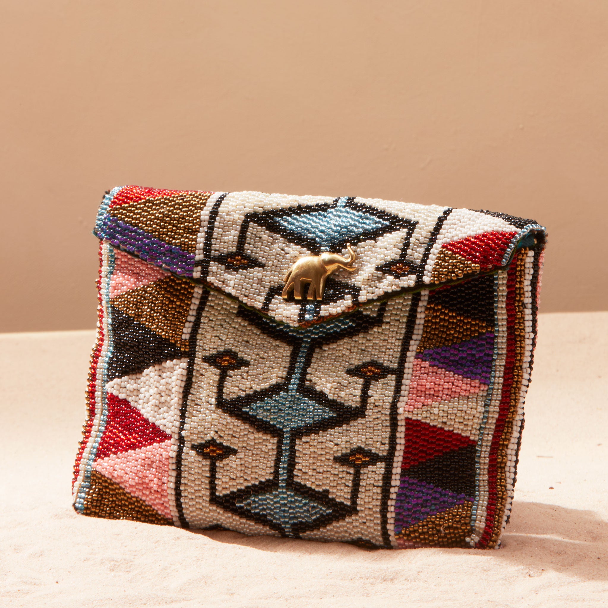 Multicolored beaded handbag with geometric pattern on a sand background