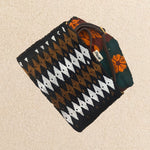 Interior view of a small beaded rectangular clutch bag with a black, brown, and white geometric diamond pattern, featuring colorful orange and green kanga fabric lining and a brown leather crossbody strap, set against a neutral beige background.