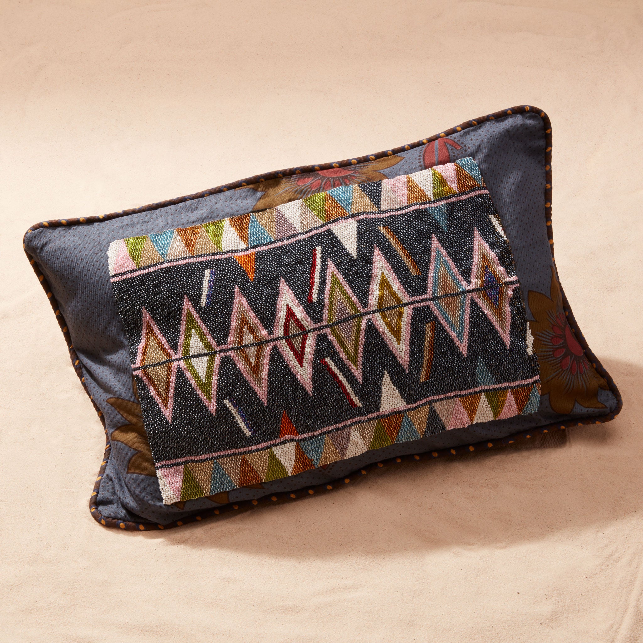 Decorative pillow with beaded geometric pattern on a beige background