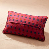 Back view of the pillow showing red fabric with blue and orange motifs
