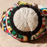 Bottom view of colorful patterned bag with a strap on a beige background