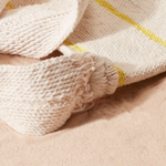 Close-up of a ivory woven bag strap on a sand background